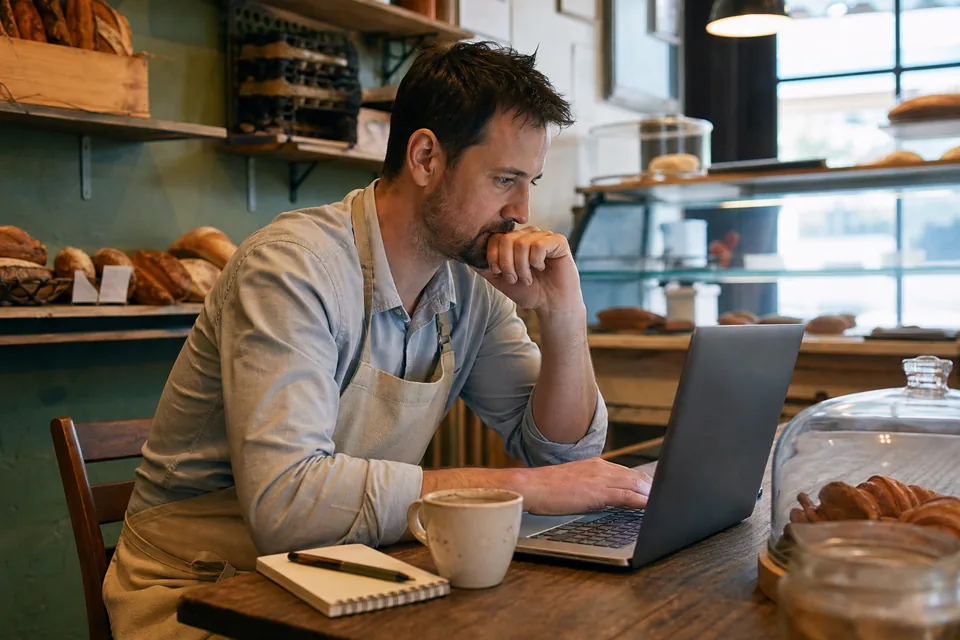 Small business owner comparing website builder plans on a laptop at a cafe table
